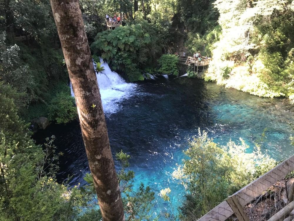 Cachoeira de águas azul-turquesa entre a mata, na região de Pucón